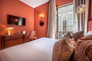 佛罗伦萨佛罗伦萨大教堂酒店的一间卧室设有橙色的墙壁和一张带窗户的床