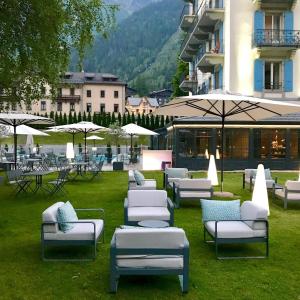夏蒙尼-勃朗峰夏蒙尼勃朗峰酒店的一群在草地上的躺椅和遮阳伞