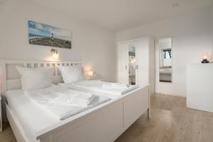 埃默尔斯比尔－霍斯比尔Ferienwohnungen Haus Schau ins Land nah an der Nordsee的白色卧室配有一张带白色床单的大床