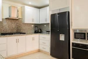 圣斐利-银港Villa Bayardo的厨房配有白色橱柜和黑色冰箱。