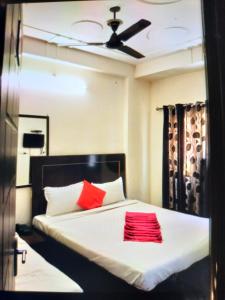 哈里瓦Hotel Shiva Haridwar - nearby bus and railway station的一间卧室配有一张带两个红色枕头的床