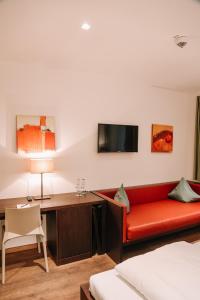 诺伊博伊埃尔恩Hotel Hofwirt Neubeuern的一间设有红色沙发和一张书桌的客房