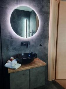 斯卡拉卡里拉奇斯Seaside Deluxe Apartment的一间带水槽和圆镜子的浴室