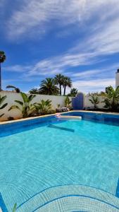 维拉诺瓦德卡塞拉Beachfront house,Manta Rota,Algarve的一个种有棕榈树的大型蓝色游泳池