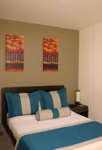 麦德林hotel medellin gold的一间卧室配有一张带蓝色和白色枕头的床
