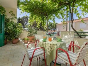 马卡尔斯卡Apartment Mario in Makarska with a nice shady terrace的庭院配有桌椅和树木