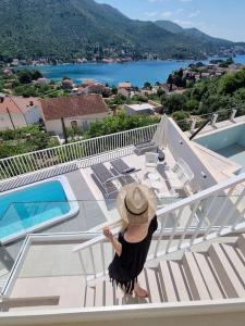 扎通Villa Ansay with heated Swim Spa pool and sea view的站在房子阳台上戴帽子的女人