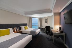 圣多明各圣多明各加泰罗尼亚酒店的酒店客房设有两张床、一张桌子和一台电视。