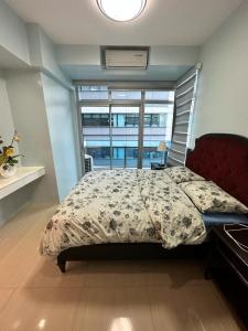 马尼拉The Pearl Interior Designed 1 BR Unit Burgos Circle BGC的一间卧室设有一张床和一个大窗户