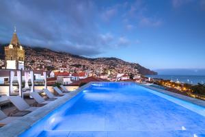 丰沙尔Barceló Funchal Oldtown的一座带椅子的建筑屋顶上的游泳池