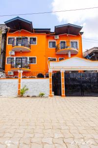 杜阿拉Clos d'Or, Appartements meublés Douala Makepé的一座橙色的建筑,设有两个阳台和车道
