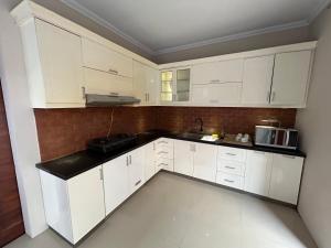 DemanganGuest House DiFi Timoho的厨房配有白色橱柜和黑色台面