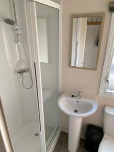 马利恩Lizard ,Mullion holiday caravan的白色的浴室设有水槽和淋浴。