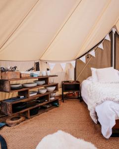 PentraethGlamping Red Wharf Bay的帐篷内的卧室,配有一张床和一张桌子