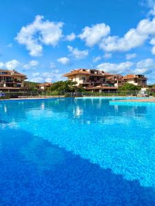 马里内拉Cala Reale Rooms Marinella的一个大型蓝色游泳池,其建筑背景为:
