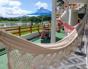 伊利亚孔普里达Recanto da Lagoa Flat的门廊上的吊床,配有桌子和遮阳伞