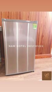 Bản CoKhach san Nam Hotel的木墙房间内的金属冰箱