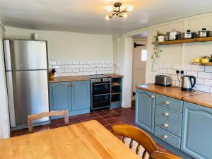埃克塞特Elbury Lodge的厨房配有蓝色橱柜、桌子和冰箱。
