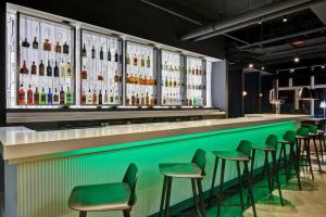 锡考克斯Aloft Secaucus Meadowlands的一间酒吧,内设绿色凳子和酒瓶