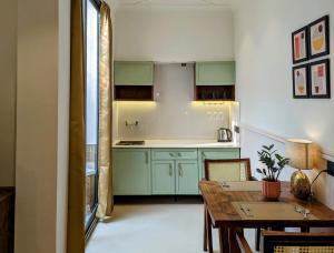 阿姆利则Cape House的厨房配有绿色橱柜和木桌