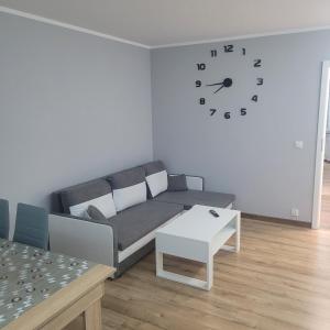 瓦尔米亚地区利兹巴克Mieszkanie centrum的客厅配有沙发和墙上的时钟