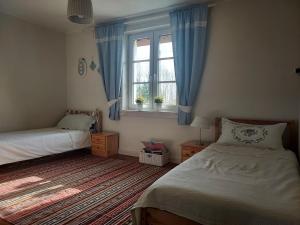 MilejczyceNa skraju lasu的一间卧室设有两张床,窗户配有蓝色窗帘