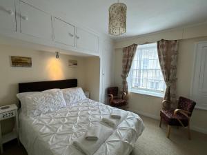 韦斯特贝The Durbeyfield Guest House的一间卧室配有一张床、两把椅子和一个窗户