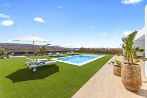 维拉韦德Villa Ayala的后院设有游泳池,草坪上设有椅子和遮阳伞