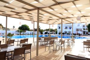 DjerbaHotel Riad Meninx Djerba的一个带桌椅的庭院和一个游泳池