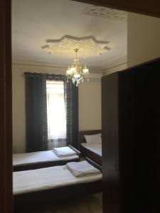 撒马尔罕Uzbek House的一间卧室设有两张床、一个吊灯和一个窗户。