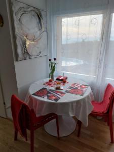 贝尔蒙叙尔洛桑Beau studio meublé POUR NON FUMEURS avec terrasse et vue的一张桌子,上面有白色的桌布和两张红色的椅子
