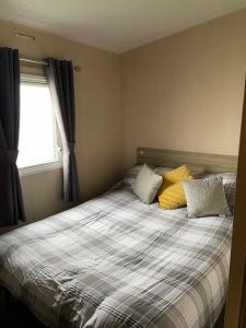 塔特舍尔9 shearwater Tattershall Lakes Country Park的一间卧室配有带两个枕头的床和窗户