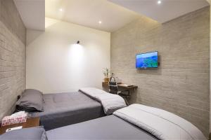 巴纳内拉斯Rahma’s B&B的一间卧室设有两张床,砖墙上配有电视
