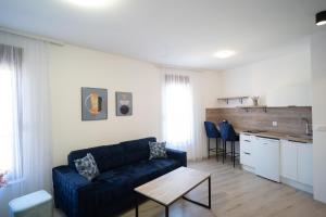莫斯塔尔Apartments and rooms SMILE的一间带蓝色沙发的客厅和一间厨房