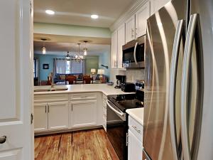 巴拿马城海滩Edgewater Villa 2406的厨房配有白色橱柜和不锈钢冰箱