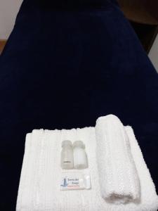 乌斯怀亚hostel comunidad Ushuaia的床上的白色毛巾和2瓶