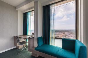 阿姆斯特丹Leonardo Hotel Amsterdam Rembrandtpark的客房设有带蓝色沙发的窗户和书桌。