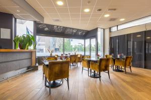 莱利斯塔德Leonardo Hotel Lelystad City Center的餐厅设有桌椅和大窗户。