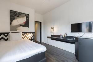 莱利斯塔德Leonardo Hotel Lelystad City Center的配有一张床和一台平面电视的酒店客房
