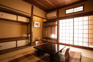 丰冈市城崎温泉 旅館 つばき乃 - Kinosaki Onsen Ryokan Tsubakino的客房设有桌子、两把椅子和窗户。