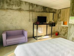 Ban Wang Takhraiปานีวิลล์ รีสอร์ต的一间卧室配有紫色沙发和电视