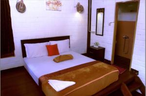 伦邦班塔尔牯岭别墅酒店的一间卧室配有一张大床,配有白色床单和红色枕头