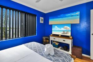 安特兰斯桑赫斯特5号公寓的一间蓝色的卧室,配有一张床和一台墙上的电视