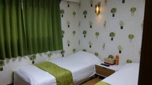 济州市济州R酒店&宾馆的一间卧室设有两张床和绿帘