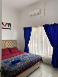 卡里蒙贾瓦Sama sama Karimunjawa的一间卧室配有一张带蓝色窗帘的床和一扇窗户