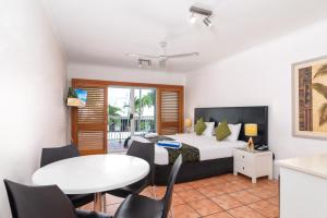 棕榈湾天堂海滩度假酒店的卧室配有一张床和一张桌子及椅子