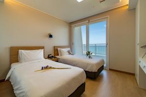 江陵市Gangneung PINEART Label的带大窗户的客房内的两张床