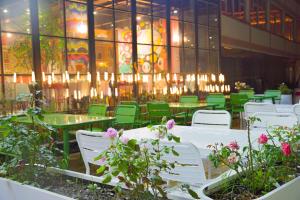 九寨沟九寨沟逍遥榻客栈的餐厅设有白色桌子和绿色椅子,并种植了鲜花