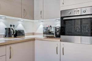 北安普敦Beautiful and Comfortable Home away from Home的厨房配有白色橱柜和黑烤箱。