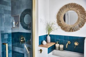 乌尔加特Maison normande face à la plage d'Houlgate的浴室铺有蓝色瓷砖,配有镜子和水槽